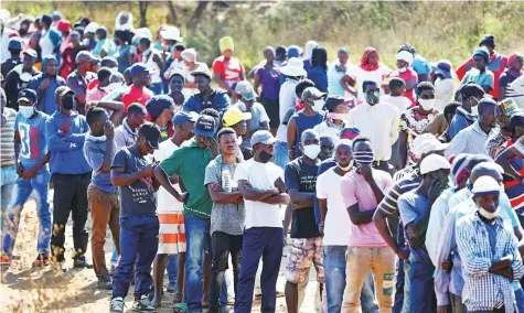  ?? Reuters ?? People wait in queues for food aid in Sunderland Ridge, South Africa. As the pandemic risks dragging them into the worst
■ economic recession on record, government­s have started to ease restrictio­ns.