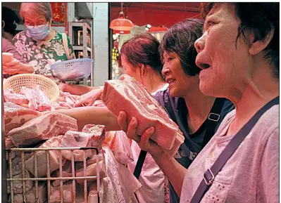  ?? AP/KIN CHEUNG ?? Customers buy frozen pork at a market in Hong Kong on May 16. A cull of swine in China, in an effort to control an outbreak of African swine fever, will lower supply in global protein markets and lead to higher meat prices, according to a report released Wednesday.