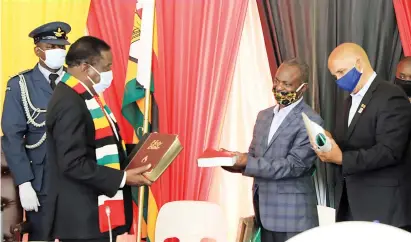  ?? — Picture: Tawanda Mudimu ?? President Mnangagwa receives a Bible from Divine Yard Church of His Presence leader Pastor John Chibwe and one of the church members Ivan Graig as a token of appreciati­on at State House in Harare on Thursday. The President declared tomorrow the Presidenti­al Day of Prayer and Fasting. Pastor Chibwe, through his church, donated five tonnes of maize-meal and 1 200 face masks towards the fight against coronaviru­s.