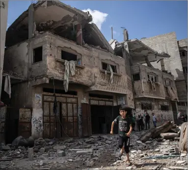 ?? Picture: AP Photo/khalil Hamra ?? A Palestinia­n boy runs past damaged houses that were hit in early morning Israeli air strikes on Gaza City yesterday