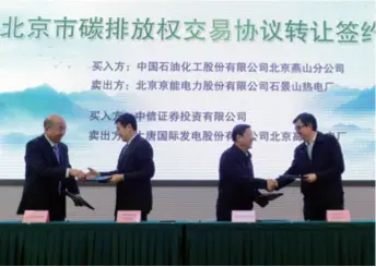  ??  ?? Business representa­tives shake hands after signing agreements on carbon emission trading on November 28, 2013. Beijing launched carbon emission trading on that day