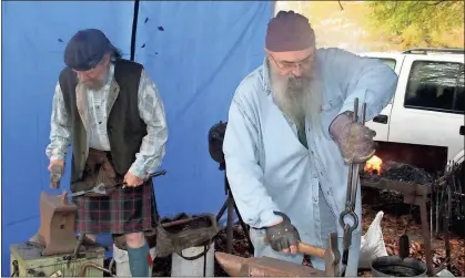  ?? / John Popham ?? Hugh Bowie (left) and Jeff Clawson, two Tennessee men with Scottish heritage, work metal into spatulas and pot holders at their blacksmith booth on Saturday. This is the third time the two have come to Cave Spring’s Small Town Christmas in the Country.