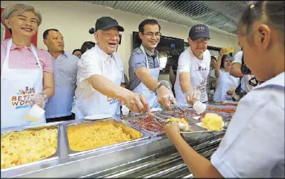  ?? EDD GUMBAN ?? San Miguel Corp. president and chief operating officer Ramon Ang and Manila Mayor Isko Moreno lead the serving of meals to Manila residents during the opening of Better World Tondo along Road 10 yesterday. Also in photo are Manila Vice Mayor Honey Lacuna and San Miguel Foods president Francisco Alejo III. The Tondo community center, formerly an idle beer warehouse, provides the poorest barangays of Manila access to food as well as the tools to help them improve their lives.