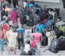  ?? PAUL CHIASSON THE CANADIAN PRESS ?? Asylum seekers line up outside Olympic Stadium near Montreal last August. Border security officers are being diverted to help with an anticipate­d influx this summer.