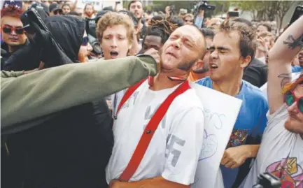  ?? Brian Blanco, Getty Images ?? A man wearing a swastika-covered shirt gets punched by an unidentifi­ed member of the crowd near the site of a speech by white nationalis­t Richard Spencer at the University of Florida in Gainesvill­e, Fla., on Thursday.