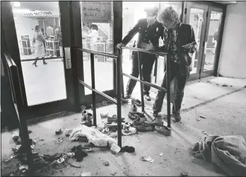  ??  ?? A security guard and an unidentifi­ed man look at an area where several people were killed Dec. 3, 1979, as they we caught in a surging crowd entering Cincinnati’s Riverfront Coliseum for a concert by the British rock band The Who. (File Photo/AP/Brian Horton)