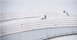  ?? COLE BURSTON/THE CANADIAN PRESS ?? Workers check damage on the Rogers Centre roof, caused by ice from CN Tower.