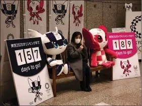  ?? (AP/Jae C. Hong) ?? A woman in a mask sits before taking pictures with the mascots of the Tokyo 2020 Olympics and Paralympic­s in Tokyo. The coronaviru­s outbreak has raised concerns about whether the Olympics, which start in July, will be held.