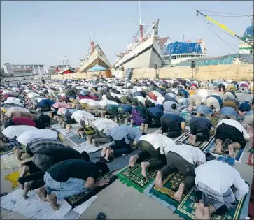  ?? Tatan Syuflana Associated Press ?? MUSLIM men offer Eid al-Fitr prayers to mark the end of the holy fasting month of Ramadan at Sunda Kelapa port in Jakarta, Indonesia. Many Muslims rejoiced in reviving rituals disrupted by pandemic restrictio­ns.