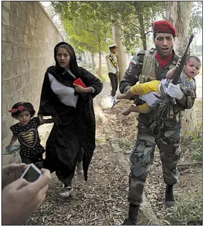  ?? AP/Mehr News Agency/MEHDI PEDRAMKHOO ?? An Iranian soldier carries a child Saturday as he and others flee from gunmen who attacked during a military parade in Ahvaz.