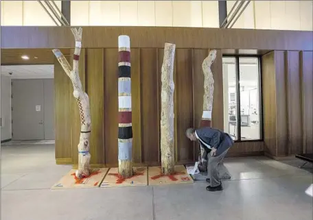  ?? Photograph­s by Brian van der Brug Los Angeles Times ?? TONGVA ancestor poles are being installed at the Autry Museum’s new Resources Center. Autry President Stephen Aron inspects.