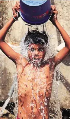  ?? AP ?? Cooling down A young boy pours a bucket of water collected from a leaking pipeline, to cool himself on the outskirts of Jammu.