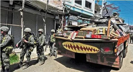  ?? — Reuters ?? Surging forward: An Armoured Personnel Carrier and troops marching towards Mapandi bridge.