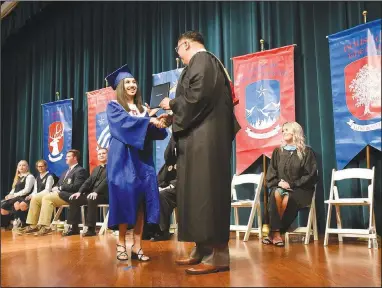  ?? (NWA Democrat-Gazette/Flip Putthoff) ?? Tania Mares receives her high school dipoloma Saturday from John Rocha, head of school at Ozark Catholic Academy in Tontitown. Twelve graduates received their diplomas at The Jones Center in Springdale. They are the first graduates of the Catholic high school, that opened in 2018. Go to nwaonline.com/210523Dail­y/ to see more photos.