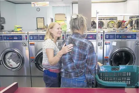  ?? Photograph­s by Don Leach Daily Pilot ?? A VOLUNTEER with Laundry Love, left, greets a client who arrives with bags of clothes at Beach Coin Laundry in Huntington Beach.