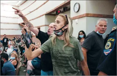  ?? (AP/Las Vegas Review-Journal/Bizuayehu Tesfaye) ?? Protesters against a covid-19 mandate gesture Aug. 12 as they are escorted out of the Clark County School Board meeting at the Clark County Government Center in Las Vegas.