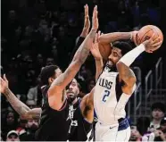  ?? Mark J. Terrill/Associated Press ?? Dallas Mavericks guard Kyrie Irving, right, tries to pass while under pressure from Los Angeles Clippers forward Paul George, left, and forward Kawhi Leonard during the second half Wednesday in Los Angeles.