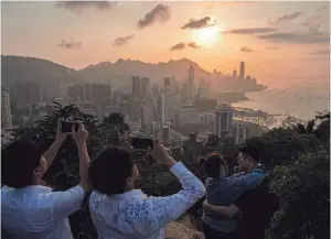  ?? LOUISE DELMOTTE/AP ?? Visitors look at sunset from a hill Friday in Hong Kong.