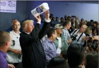  ?? EVAN VUCCI — THE ASSOCIATED PRESS FILE ?? President Donald Trump tosses paper towels into a crowd as he hands out supplies at Calvary Chapel, Tuesday in Guaynabo, Puerto Rico. Trump is in Puerto Rico to survey hurricane damage.