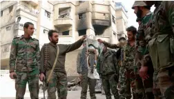  ?? — AFP ?? Syrian pro- government fighters burn a Faylaq al- Rahman militant group's flag as they search for weapon caches in the town of Hazzeh in Eastern Ghouta, on the outskirts of the Syrian capital Damascus, on Tuesday.