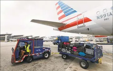  ?? Allen J. Schaben Los Angeles Times ?? A VEHICLE pulls luggage unloaded from an American Airlines f light to the baggage claim in Orlando, Fla.