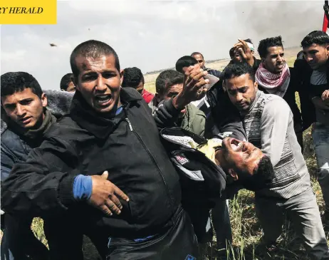  ?? SAID KHATIB / AFP / GETTY IMAGES ?? An injured Palestinia­n man is carried by fellow protesters as they run for cover during clashes with Israeli security forces in the Gaza Strip on Friday. At least 15 people were killed, with the Palestinia­n Health Ministry claiming more than 750 wounded in the encounter.