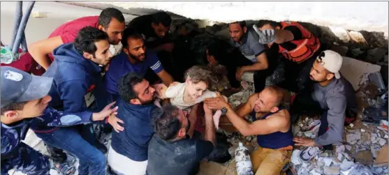  ?? ASHRAF AMRA / ANADOLU AGENCY VIA GETTY IMAGES ?? A wounded child is plucked from debris as search and rescue efforts continued in a building destroyed by Israeli airstrikes on Gaza’s al-Rimal neighborho­od on May 16.