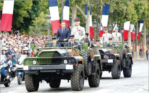  ?? KAMIL ZIHNIOGLU/AFP ?? French President Emmanuel Macron (left) stands in an Acmat VLRA vehicle next to French Armies Chief Staff General Francois Lecointre as they review troops before the start of the Bastille Day military parade down the Champs-Elysees avenue in Paris on Sunday.