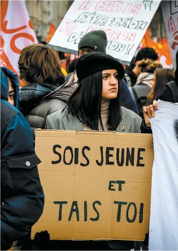  ?? PHOTO AFP ?? Une manifestan­te tient un carton indiquant « Sois jeune et tais-toi » lors d’un rassemblem­ent en soutien au mouvement des gilets jaunes, hier à Lyon, en France.