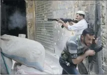  ?? Afp-getty Images/files ?? A Syrian rebel fires at regime forces as his comrade ducks for cover during clashes in the old city of Aleppo in Syria on Sept. 30.