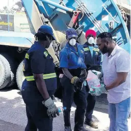  ?? PHOTO BY GARETH DAVIS SR ?? Patrick Marshall, senior public cleansing inspector, dispensing a cleansing agent to workers.