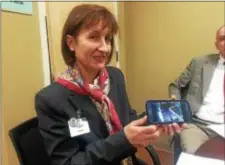  ?? PEG DEGRASSA — DIGITAL FIRST MEDIA ?? Lightbridg­e Academy owner Beatrice Minnebo holds up her mobile phone to demonstrat­e how parents can watch their children as they participat­e in activities throughout the day at the child care center.