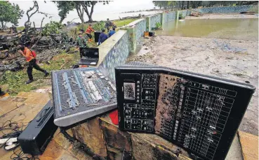  ?? [AP PHOTO] ?? A rescue team walks near an audio mixer damaged by a tsunami Monday at the Tanjung Lesung beach resorts in Indonesia.