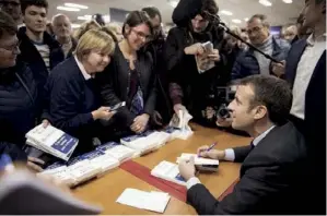  ??  ?? Macron (ci-dessous, dédicaçant son livre à Evreux, le 2 décembre) doit maintenant étendre l’assise populaire de son mouvement.