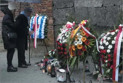  ?? CZAREK SOKOLOWSKI — THE ASSOCIATED PRESS ?? Holocaust survivors and relatives place candles next to the Death Wall in the Auschwitz Nazi death camp in Oswiecim, Poland, on Saturday.