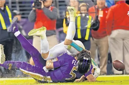  ?? JIM RASSOL/STAFF PHOTOGRAPH­ER ?? Ravens quarterbac­k Joe Flacco’s helmet goes flying as he is hit by Dolphins middle linebacker Kiko Alonso in the second quarter of Thursday’s game in Baltimore. Alonso was penalized for unnecessar­y roughness.