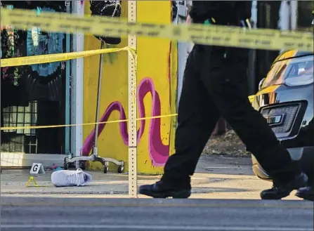  ?? POLICE OFFICERS Kent Nishimura Los Angeles Times ?? assess the scene Dec. 15 at Melrose Avenue in the Fairfax district of Los Angeles, after a shooting killed one man and left another in critical condition. Shootings in 2020 increased nearly 40% from the previous year, and homicides rose nearly 38%.