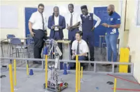  ?? ?? Former state minister, Ministry of Culture, Gender, entertainm­ent and Sport Alando Terrelonge (second left) operates a robot that was designed, built and programmed by the Jamaica College (JC) robotics team. Team members include (from left): Michael Woods, Delano Reid, Stanley Cai, Orville Daley, and Team Manager Jason Brown.