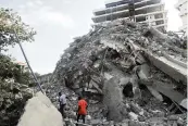  ?? PIUS UTOMI EKPEI AFP via Getty Images/TNS ?? People walk amid the rubble of a 21-story building that collapsed in Lagos, Nigeria, on Monday.