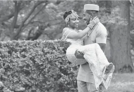  ?? AMY DAVIS/BALTIMORE SUN ?? Christin Young, is carried by her fiance, Ikenna Uzomah, both of Largo, as they pose for photos at Cylburn Arboretum to celebrate their engagement. They are optimistic that plans for their two weddings, the first a traditiona­l Nigerian wedding in the late fall in Upper Marlboro, and then a destinatio­n wedding in Jamaica in January, will not be affected by the coronaviru­s pandemic.