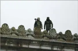  ?? TED S. WARREN — THE ASSOCIATED PRESS ?? On Monday, law enforcemen­t officers stand atop the state Capitol in Olympia, Washington, in anticipati­on of protests.