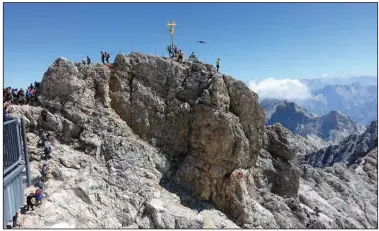  ?? (Rick Steves/TNS) ?? A golden cross marks the top of the 9,700-foot Zugspitze, the highest point in Germany. The mountain straddles the border between Germany and Austria, and lifts from both countries whisk visitors to the top.