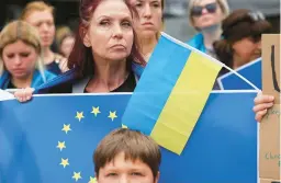  ?? OLIVIER MATTHYS/AP ?? Supporters of Ukraine’s inclusion in the European Union show their approval Thursday outside the EU summit in Brussels. The bloc approved the action unanimousl­y.