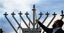  ?? NICK OZA/THE REPUBLIC ?? Rabbi Dov Levertov lights the first candle as Hannukah begins at sundown in front of Wesley Bolin Plaza in Phoenix, Dec. 12, 2017.