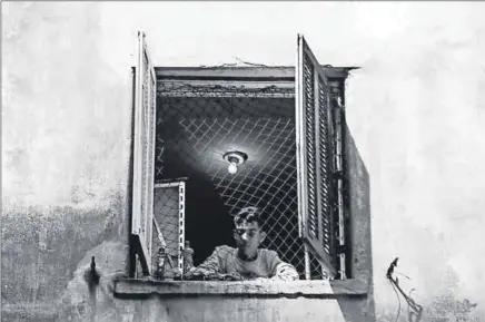  ??  ?? Neighbourh­ood watch: A boy stares out of the window of an unoccupied building in São Paulo. Social movements have been using loopholes in the Constituti­on to redress housing backlogs. Photo: Alessandro Vecchi