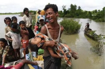  ?? FOTO AFP ?? Een Rohingya-vluchtelin­g steekt met zijn dode zoon in de armen de grens van Myanmar naar Bangladesh over.