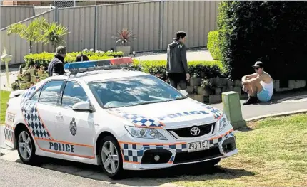  ?? PHOTO: KEVIN FARMER ?? EXPLOSION: People and police wait in front a Harristown home where two teenagers received serious burns in a backyard fire explosion.