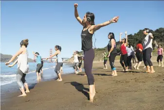  ?? Scott Strazzante / The Chronicle ?? Julie Aiello (center) leads a yoga class under clear skies at San Francisco’s Baker Beach.