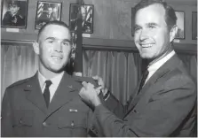  ?? Associated Press ?? ■ In this 1968 file photo provided by the Texas National Guard, George H.W. Bush, right, is about to pin a lieutenant bar on his son George W. Bush after the younger Bush was made an officer in the Texas Air National Guard in Ellington Field, Texas.