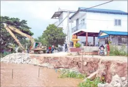  ?? HONG MENEA ?? A bulldozer puts rocks on a riverbank to prevent further collapse in Chroy Changvar district.